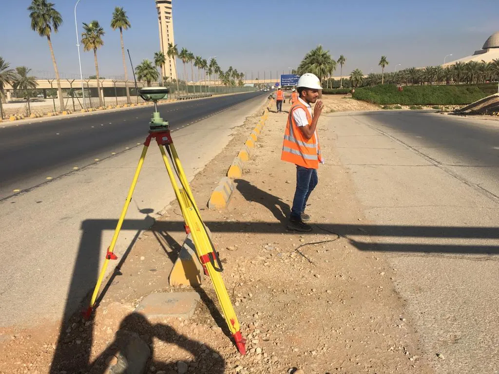 Surveyor with a GNSS receiver on a tripod beside Airport Road, Riyadh