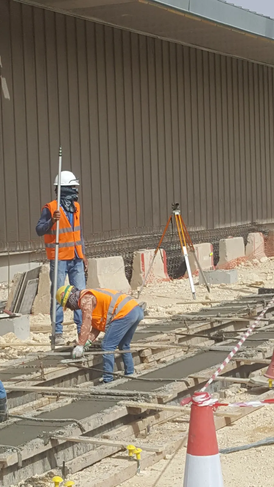 Surveyor holding a levelling staff over depot foundations