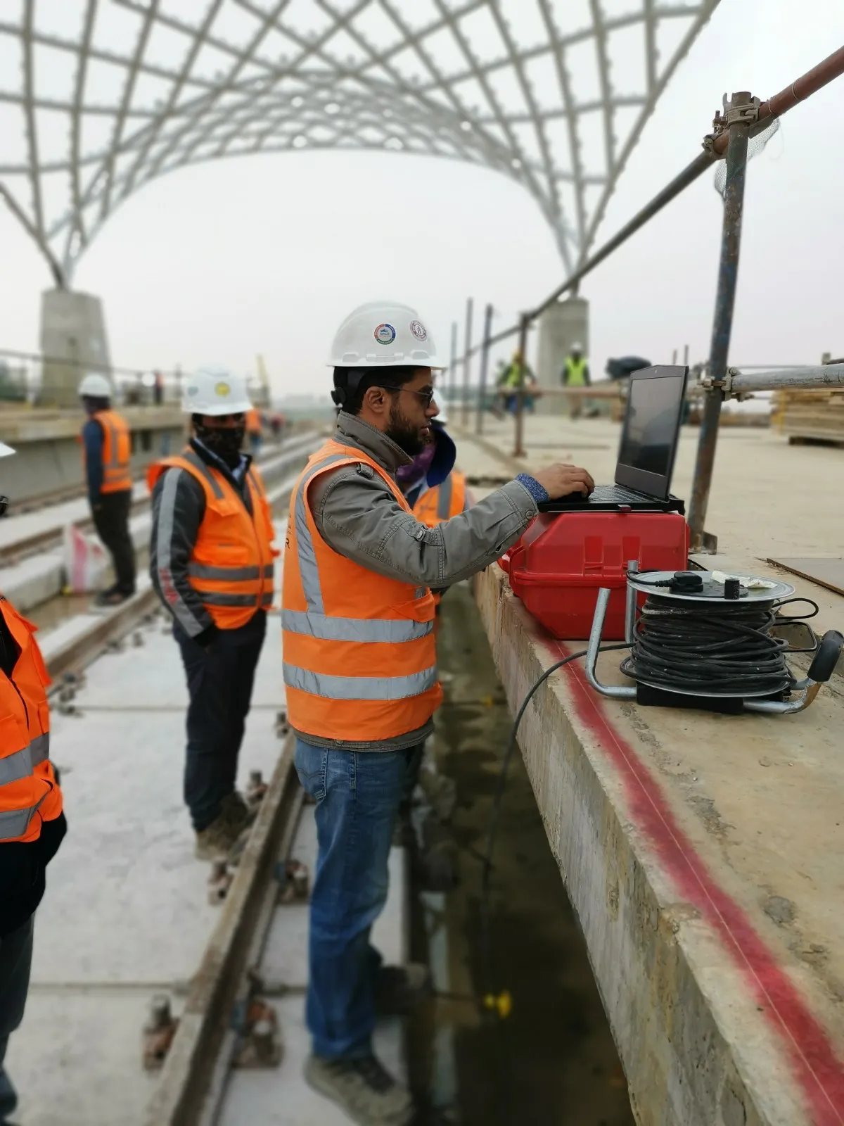 Surveyor logging instrument data on a laptop on a metro viaduct